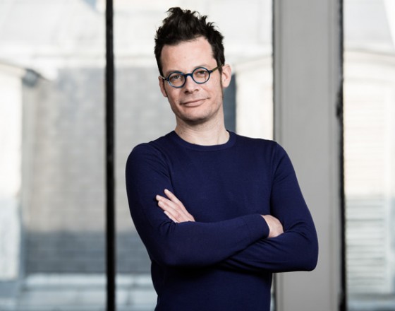 Paul Gillet, fondateur de Leibniz, bras croisés devant une fenêtre